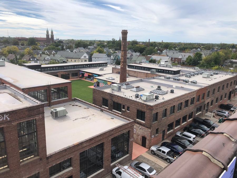 Aerial view of an adaptive-reuse brick industrial building converted to multifamily residential, with rooftop courtyard